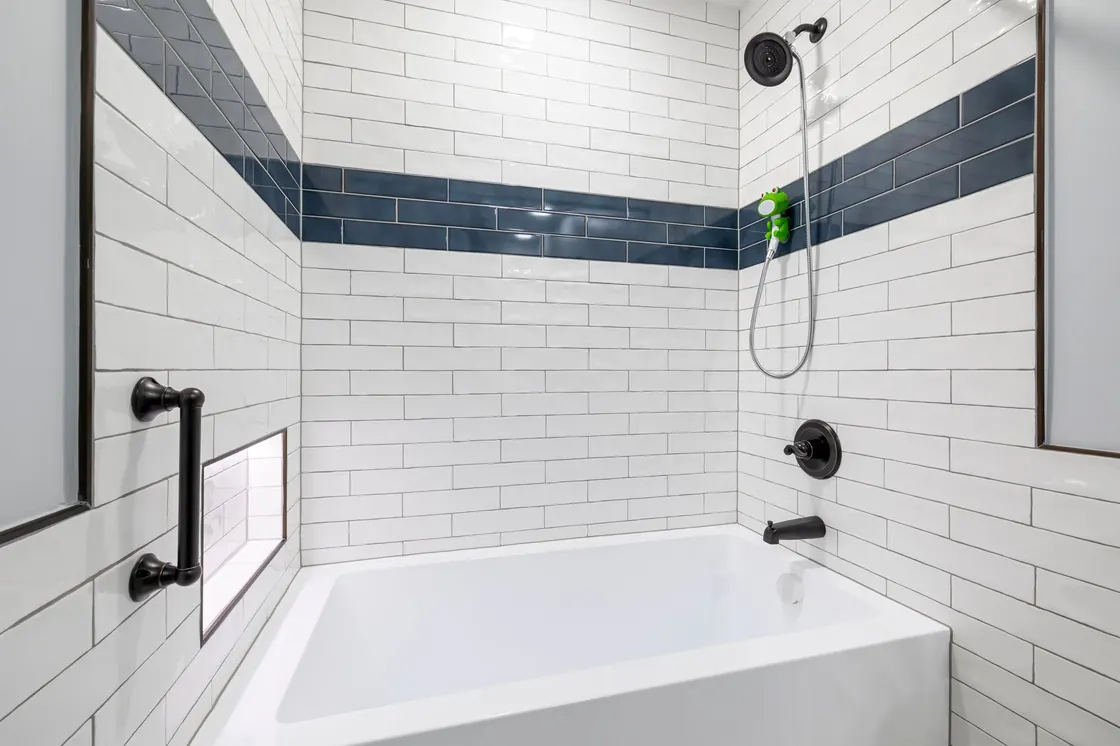 A clean modern bathroom with white tile and gleaming chrome fixtures